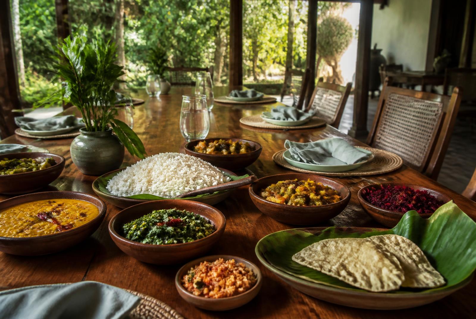 Rice and vegetable curries in clay bowls on a long timber table